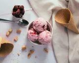 Schüssel mit drei Kugeln Kirscheis, daneben Waffeln und Kirschen. Man fragt sich, wie viel Kalorien hat eine Kugel Eis.