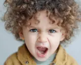 Niño de 1 año con rizos castaños, ojos marrones y expresión de enfado. Las rabietas son parte del desarrollo.