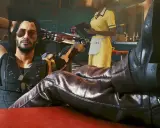 Un hombre con brazo cibernético y tatuajes, con las botas puestas sobre una mesa, como en una guía de Cyberpunk 2077.