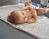 Bebé acostado en una manta con estrellas, mientras le cambian el pañal. Un paso más para dejar el pañal.