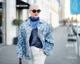 Kobieta w oversize'owej jeansowej katanie z nadrukiem, niebieskiej koszuli i błyszczącym topie.