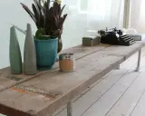 Une table basse rustique, idéale pour savoir que faire avec des vieilles planches de bois. Elle est décorée d'une machine à écrire, de vases et d'une bougie.