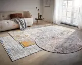 Mattor inspiration: En rund och två rektangulära mattor med abstrakt mönster i grått, vitt, gult och rött ligger på ett betonggolv framför en soffa.