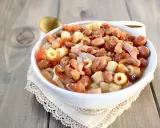 Una ciotola di pasta e fagioli in scatola, con pomodoro e pancetta, servita su un tovagliolo di pizzo.