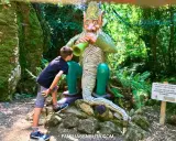 Un niño observa fascinado una figura de duende en un bosque de Cantabria con niños. ¡Una aventura mágica!