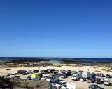 Día soleado en Lanzarote con niños. Coches aparcados en la playa, familias disfrutando del mar y la arena.