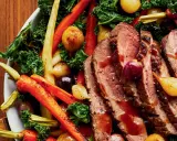 Tranches de magret de canard juteux, accompagnées de carottes rôties, d'oignons grelots et de chou frisé. Un plat savoureux et coloré.