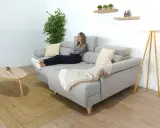 Mujer relajada en un cómodo sofá en medio del salón, con una manta y cojines.