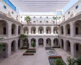 Hof des Malaga Museums mit Arkaden, Palmen und einem Brunnen.