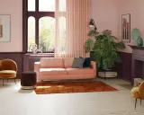Przytulny salon z sofą w kolorze pudrowy róż, aksamitnym fotelem i dywanem w odcieniu miedzi.