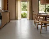 Cocina moderna con muebles de madera y un elegante suelo microcemento que refleja la luz natural.