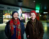 Två glada personer vid en biljettkiosk, redo att se filmer på bio nu.