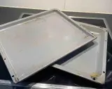 Zwei eingebrannte Backbleche liegen auf einem Cerankochfeld. Zeit, sie zu reinigen und wieder glänzen zu lassen!