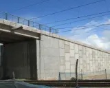 El estribo del puente de hormigón se alza imponente, sosteniendo la estructura sobre las vías del tren.