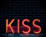 Neonowy napis KISS na tle ceglanej ściany. Zasada KISS: Keep It Simple, Stupid.