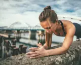 Frau macht Liegestütze am Ufer, um ihren Körper fit zu halten. Training im Urlaub ist möglich!
