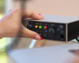 Dłoń z czerwonym lakierem na paznokciach dotyka panelu urządzenia, pokazując jak podłączyć mio smartbox iii.