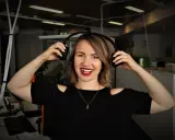Uśmiechnięta kobieta z słuchawkami na uszach, słucha podcastów do nauki angielskiego.