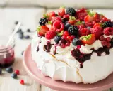 Beza pavlova która zawsze wychodzi, udekorowana bitą śmietaną i mnóstwem świeżych owoców leśnych.