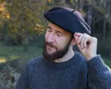 Hombre con barba ajustando su boina de lana, ideal para aprender como hacer una boina de lana.