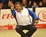 Un joueur de pétanque français connu, en pleine action, lance sa boule.