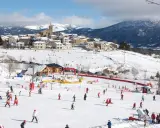 Un pueblo nevado en el Pirineo francés con niños esquiando y divirtiéndose en la nieve.