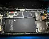Rozkręcony iPhone z widoczną baterią i procesorem A15 Bionic. Wygląda na to, że ten zalany iPhone wymaga pilnej naprawy.