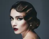 Glamouröse Frau mit einer eleganten 20er Jahre Frisur, dramatischem Make-up und einem Perlenohrring.