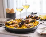 En härlig paella med skaldjur och ris, perfekt att avnjuta med ett glas vitt vin till paella. Serveras med citronklyftor och oliver.