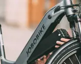 Ręce wyjmujące czarną baterię z ramy roweru elektrycznego JOBORBIKE.