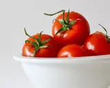 Cztery soczyste pomidory w białej misce. Niska zawartość pomidor kcal sprawia, że są idealne na zdrową przekąskę.