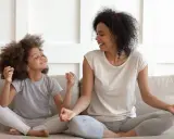 Madre e hija meditando juntas, fomentando sus habilidades de afrontamiento. Ambas sonríen y parecen relajadas.