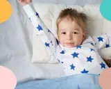 Niño de 3 años, con pijama de estrellas, estirándose en la cama.