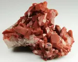 Grappolo di cristalli di quarzo rosso, con sfaccettature lucide. Il quarzo rosso significato è legato all'energia vitale e alla passione.