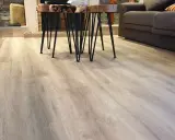 El suelo laminado o parquet de madera clara se extiende por la sala, reflejando la luz.