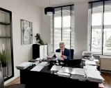 Adwokat w garniturze siedzi przy biurku w gabinecie, przeglądając dokumenty.