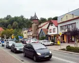 Tłoczny dobczyce rynek z wieżą zegarową, samochodami i skuterem.