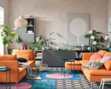 Un salon moderne avec deux canapés orange vif. Un tapis rond aux couleurs vives et des plantes vertes apportent de la vie. L'idée est d'associer 2 canapés différents pour un style unique.