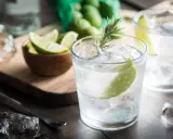Kto pije gin z tonikiem? Orzeźwiający drink z lodem, limonką i rozmarynem, gotowy do degustacji.