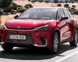 El Lexus LBX rojo brillante se desplaza por una carretera rural, con un paisaje seco y rocoso de fondo.