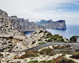 Carretera sinuosa en acantilados rocosos con vistas al mar azul. Un viaje en coche por un paisaje espectacular.