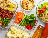 Gotowe pojemniki z jedzeniem na biwak bez gotowania: ryż z fasolą i pieczarkami, warzywa pokrojone w słupki, kalafior, sałatka z pomidorami i awokado, hummus i napoje.