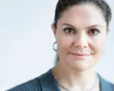 Kronprinsessan Victoria ålder. En närbild av hennes ansikte med bruna ögon och ett leende. Hon bär en grå kavaj och ett silverhalsband.