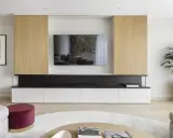 Un moderno mueble de salón con una gran televisión para poner la tele en medio del salón. Destacan los paneles de madera clara y los cajones blancos.