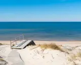 Drewniane schody prowadzące na piaszczystą plażę nad spokojnym Bałtykiem.