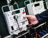 Dłoń manipuluje przy liczniku zdalnego odczytu PGE. Nowoczesne urządzenia do monitorowania zużycia energii.