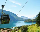 Cabina panoramica sul lago di Molveno, con montagne sullo sfondo. Si intravede una cascata tra gli alberi.