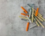 Montón de tacos de pared de varios colores (naranja, beige, gris) con tornillos. Listos para fijar cualquier cosa a la pared.