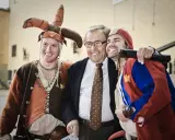 Jonas Elgh skrattar med två män i medeltida kläder. En har en narrmössa, den andra en röd och blå dräkt.