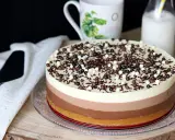 Deliciosa tarta de tres chocolates, con capas de blanco, con leche y negro, cubierta de virutas y bolitas de chocolate.